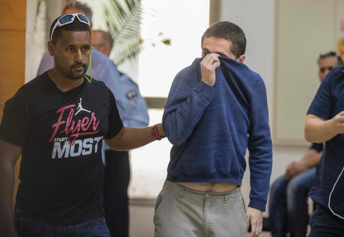American-Israeli Jewish teenager (R), accused of making dozens of anti-Semitic bomb threats in the United States and elsewhere, is escorted by guards as he leaves the Israeli Justice court in Rishon Lezion. (AFP)