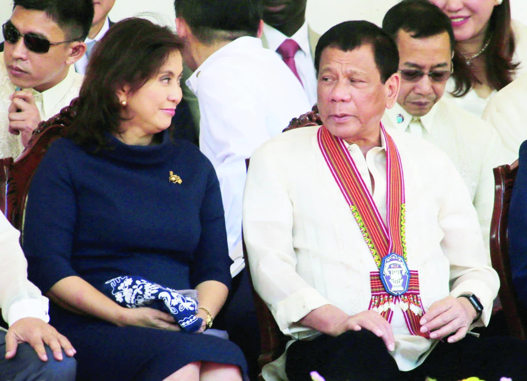 Philippine President Rodrigo Duterte talks to Vice President Leni Robredo during the police graduation ceremony in Camp Castaneda on Friday. (Reuters)