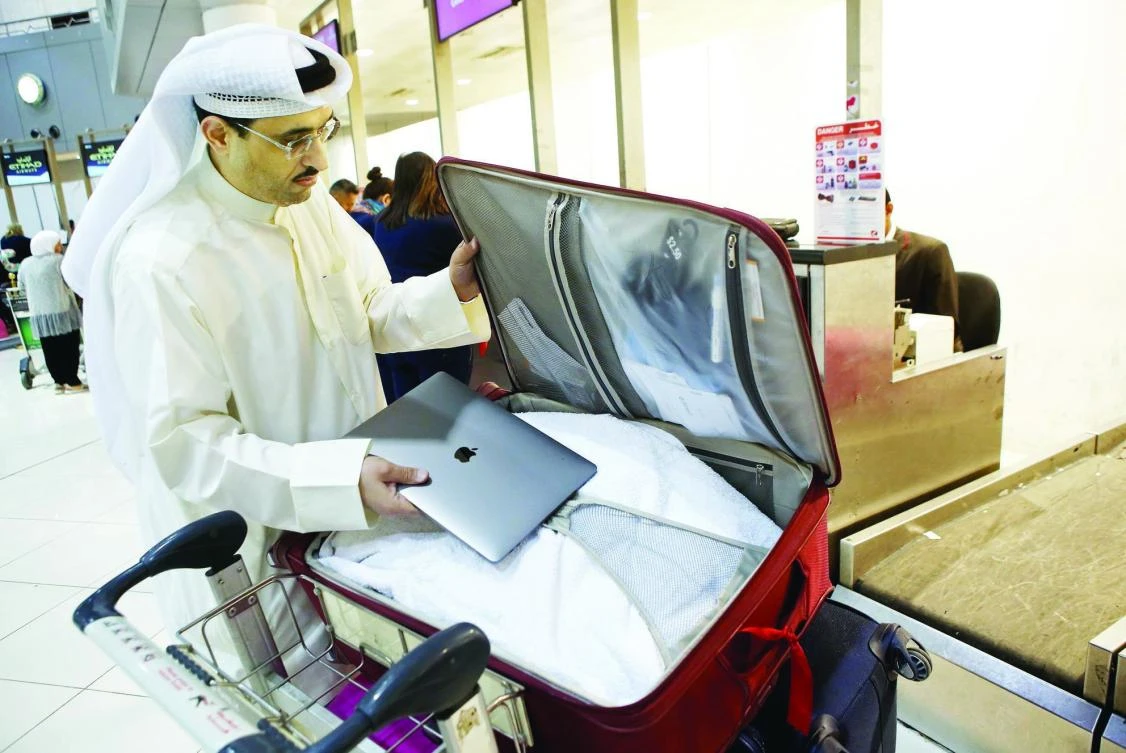 A flier puts his laptop inside his suitcase before boarding a flight to the US in Kuwait. (AFP)