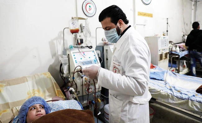 Kidney specialist Mohamed Sadeq, a 34-year-old Syrian physician, stands next to his patient Dania, a 14-year-old who suffers from renal insufficiency, as she undergoes treatment in the basement-turned-clinic in the rebel-held town of Douma, on the outskirts of the capital Damascus, in this February 9, 2017 photo. (AFP)