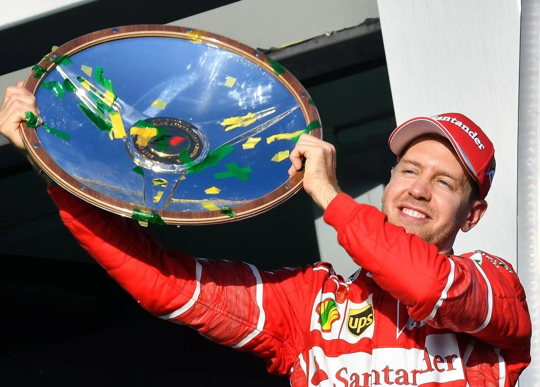 Ferrari's German driver Sebastian Vettel celebrates with the winner's trophy on the podium following his victory in the Australian Grand Prix in Melbourne on Sunday. (AFP)