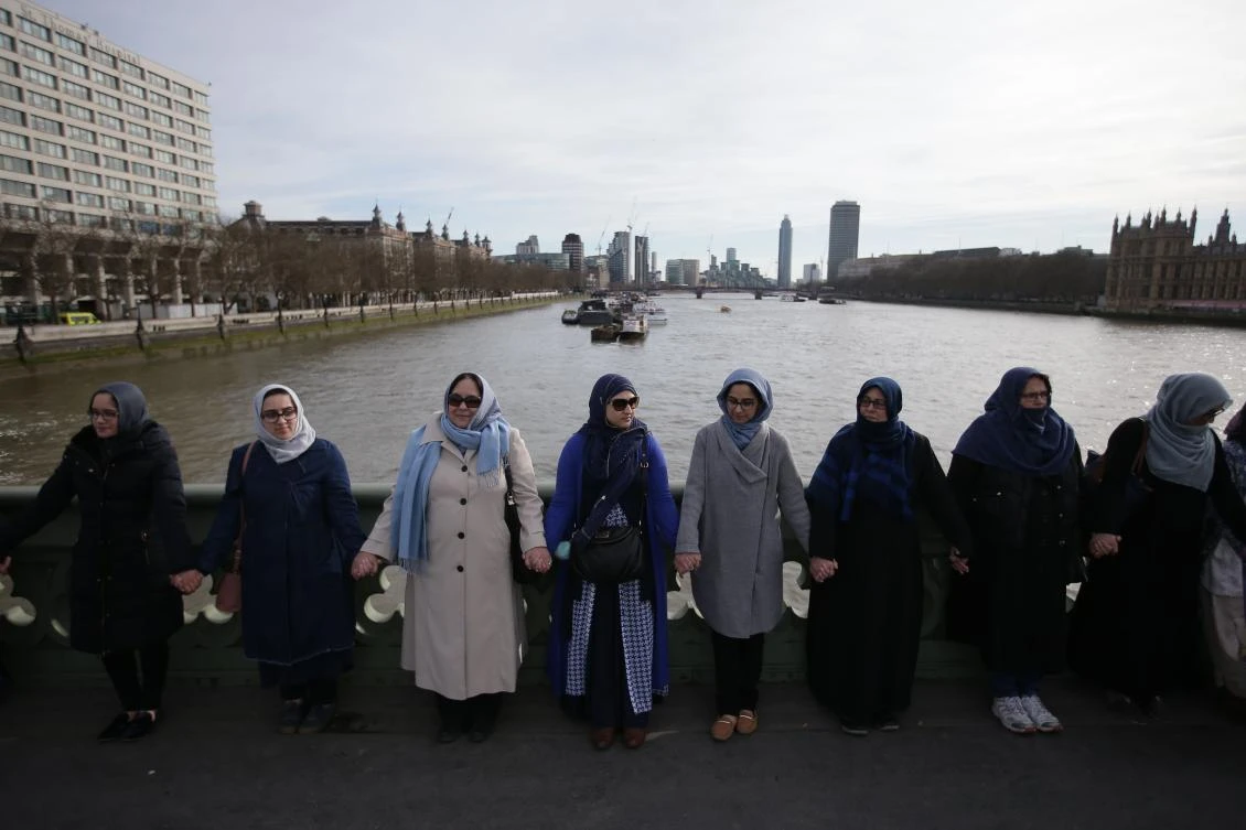 Women activists wearing blue hold hands on Westminster Bridge in front of the Houses of Parliament to honour the victims of the March 22 attack in central London on March 26, 2017. (AFP)
