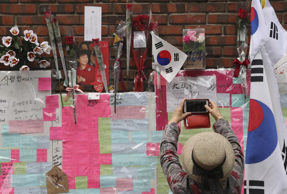 A supporter of former South Korean President Park Geun-hye takes photo with smartphone in front of the wall of Park's private home in Seoul, South Korea. (AP)