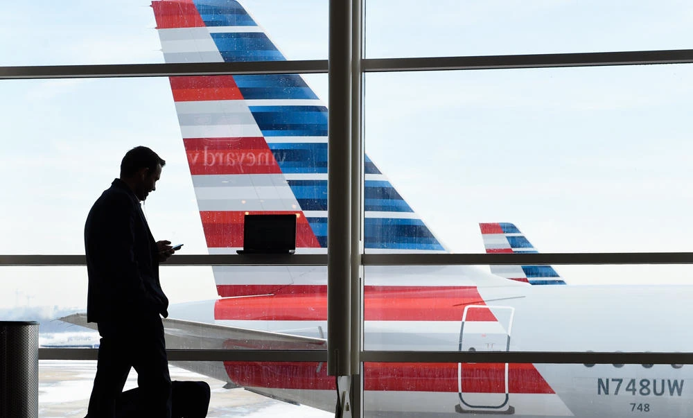 A passenger talks on the phone as American Airlines jets sit parked at their gates at Washington's Ronald Reagan National Airport. (AP)