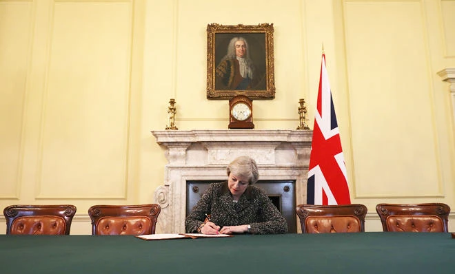British Prime Minister Theresa May in the cabinet, sitting below a painting of Britain's first Prime Minister Robert Walpole, signs the official letter to European Council President Donald Tusk invoking Article 50 and the United Kingdom's intention to leave the EU on March 28, 2017 in London, England. (Reuters)