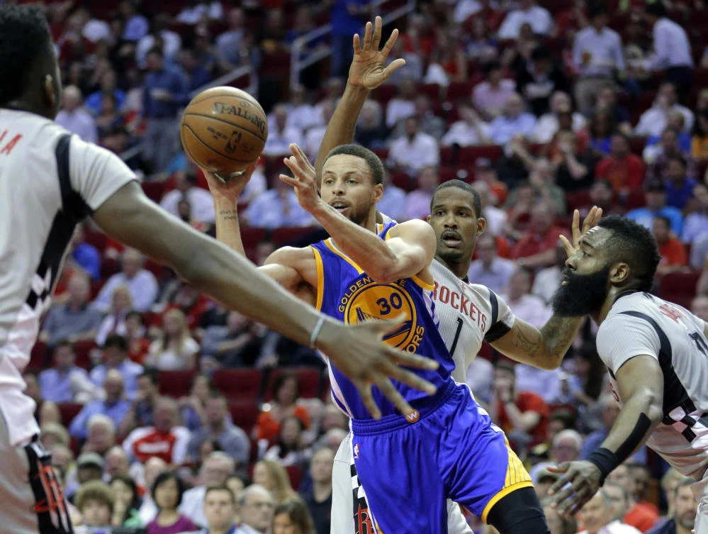 Golden State Warriors' Stephen Curry (30) dishes the ball between Houston Rockets' Clint Capela, Trevor Ariza (1) and James Harden (13) in the first half of an NBA basketball game in Houston Tuesday. (AP)
