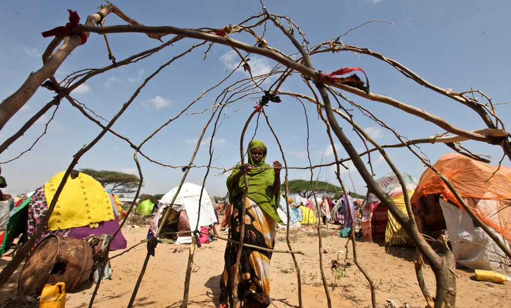 A newly displaced Somali uses sticks to build a makeshift shelter at a camp in the Garasbaley area on the outskirts of Mogadishu, Somalia. (AP)