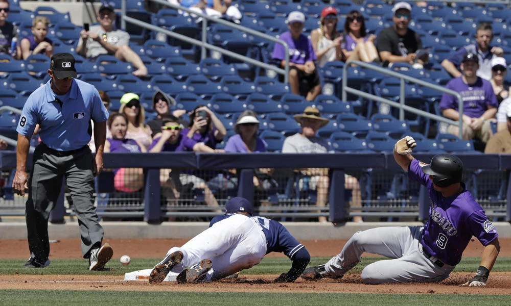 Colorado Rockies' DJ LeMahieu slides safe into third as the throw get past San Diego Padres' Allen Cordoba during the first inning of a spring training baseball game on Thursday in Peoria, Arizona. (AP Photo/Darron Cummings)