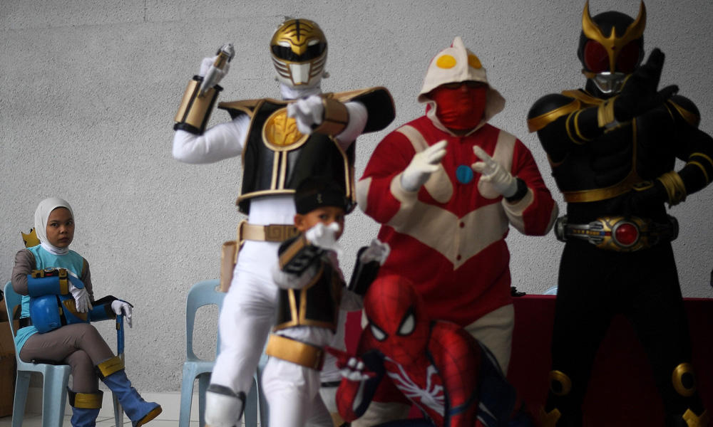 Azlyna Zaina (L), a young Muslim cosplayer dressed as a character from the "Power Rangers", looks on as participants pose for photographs during the "Hijab Cosplay" event in Subang Jaya, outside of Kuala Lumpur, on Saturday. (AFP / Manan Vatsyayana)