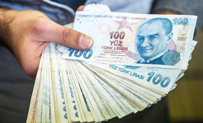 A change office staff shows Turkish lira on his hand on December 2, 2016 in Istanbul. (AFP)