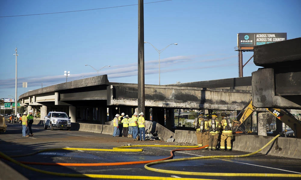 Construction workers and firefighters survey a section of an overpass that collapsed from a large fire on Interstate 85 in Atlanta on Friday. (AP Photo/David Goldman)