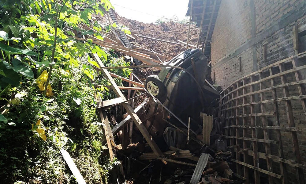 This handout photograph taken and received on Saturday by Indonesia's National Disaster Agency shows a trapped car and debris following a landslide that hit Banaran village in Ponorogo, East Java province, on April 1, 2017. Seventeen people have gone missing and feared to be buried after a landslide struck Indonesia, the national disaster agency said. (AFP)