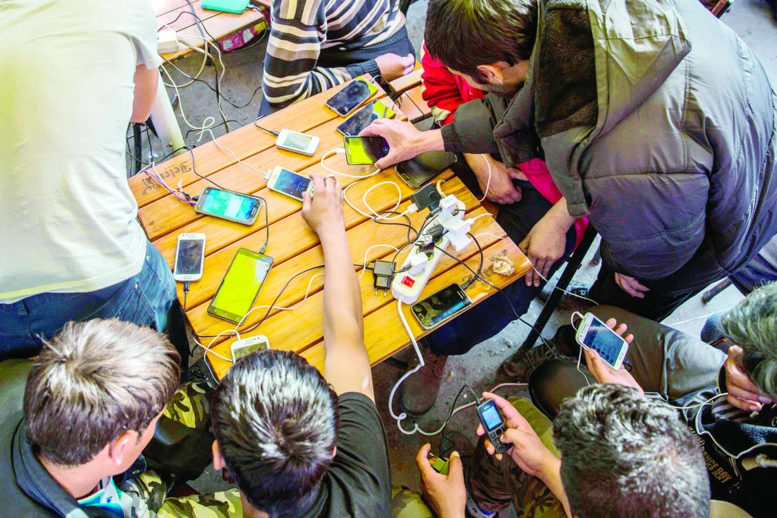 Migrants charge their mobile phones in a restaurant near the central bus station in Belgrade earlier this month. (AFP)