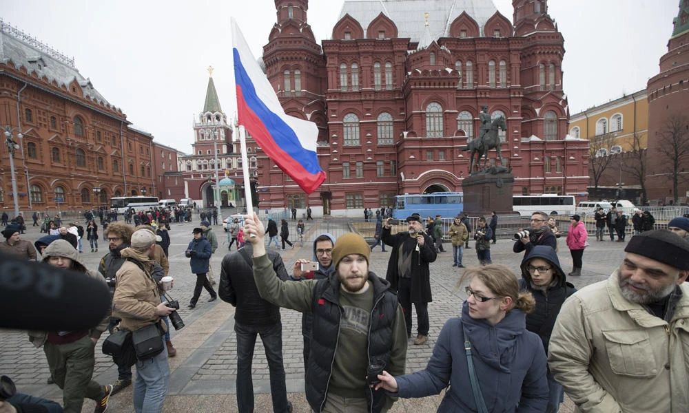 A man walks holding a Russian national flag in front of the Historical Museum near Red Square in Moscow on Sunday. Russian prosecutors moved Friday to block calls on social networks for more street protests in Moscow and other Russian cities following a wave of rallies that have cast a new challenge to the Kremlin. (AP Photo/Pavel Golovkin)