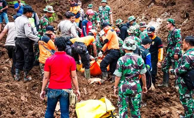 Indonesian rescuers recover the body of a woman from the scene after a wall of mud slammed onto houses from a hillside following heavy rainfall in Ponorogo district, East Java on Sunday. (AFP)