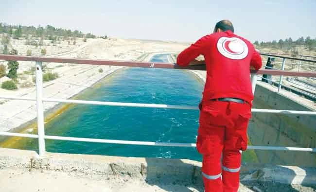 A Syrian Arab Red Crescent member is seen examining water levels at the Tabqa dam on Tuesday. (AFP)