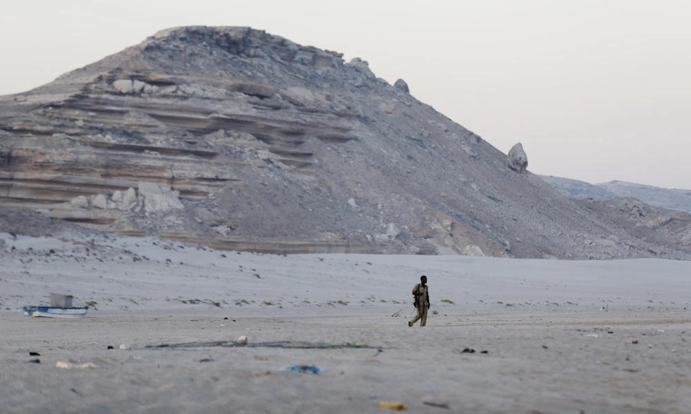 In this photo taken Monday, March 6, 2017, a Somali government soldier walks on the beach in Eyl, in Somalia's semiautonomous northeastern state of Puntland. Somali pirates have seized a small boat, kidnapped its Indian crew members, and are taking the vessel to the Eyl area of northern Somalia, an investigator said Monday, the latest vessel targeted by the region's resurgent hijackers. (AP Photo/Ben Curtis)
