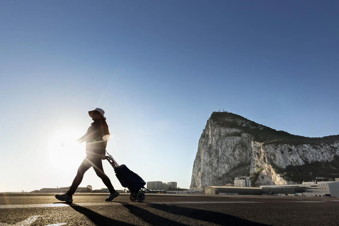 A woman walks on the Spanish side of the border between Spain and the British overseas territory of Gibraltar with the Rock as a background. (AP Photo/Daniel Ochoa de Olza, File)