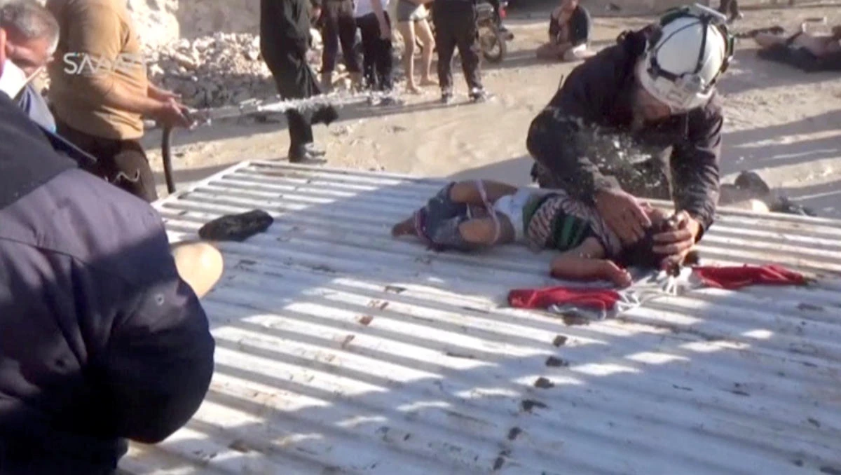 A still image taken from a video posted to a social media website on April 4, 2017, shows a civil defense member helping a child who is being sprayed with water, said to be in the town of Khan Sheikhoun, after what rescue workers described as a suspected gas attack in rebel-held Idlib, Syria. (Social Media Website via Reuters TV)