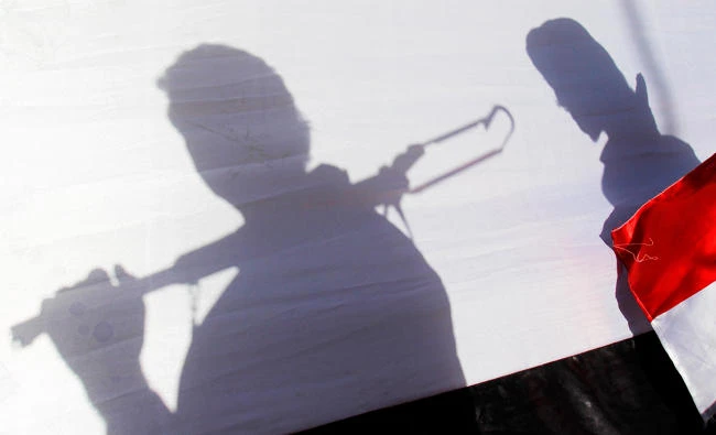 In this April 16, 2015 file photo, The shadow of Shiite rebels, known as Houthis, are cast on a large representation of the Yemeni flag as they attend a demonstration against an arms embargo imposed by the U.N. Security Council on Houthi leaders, in Sanaa, Yemen. (AP)
