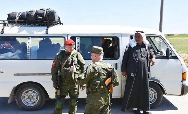 Members of the Russian Military police stand guard in the northern city of Manbij as Syrians who fled the city of Aleppo due to the fighting prepare to return to their hometown, on Wednesday. (AFP)