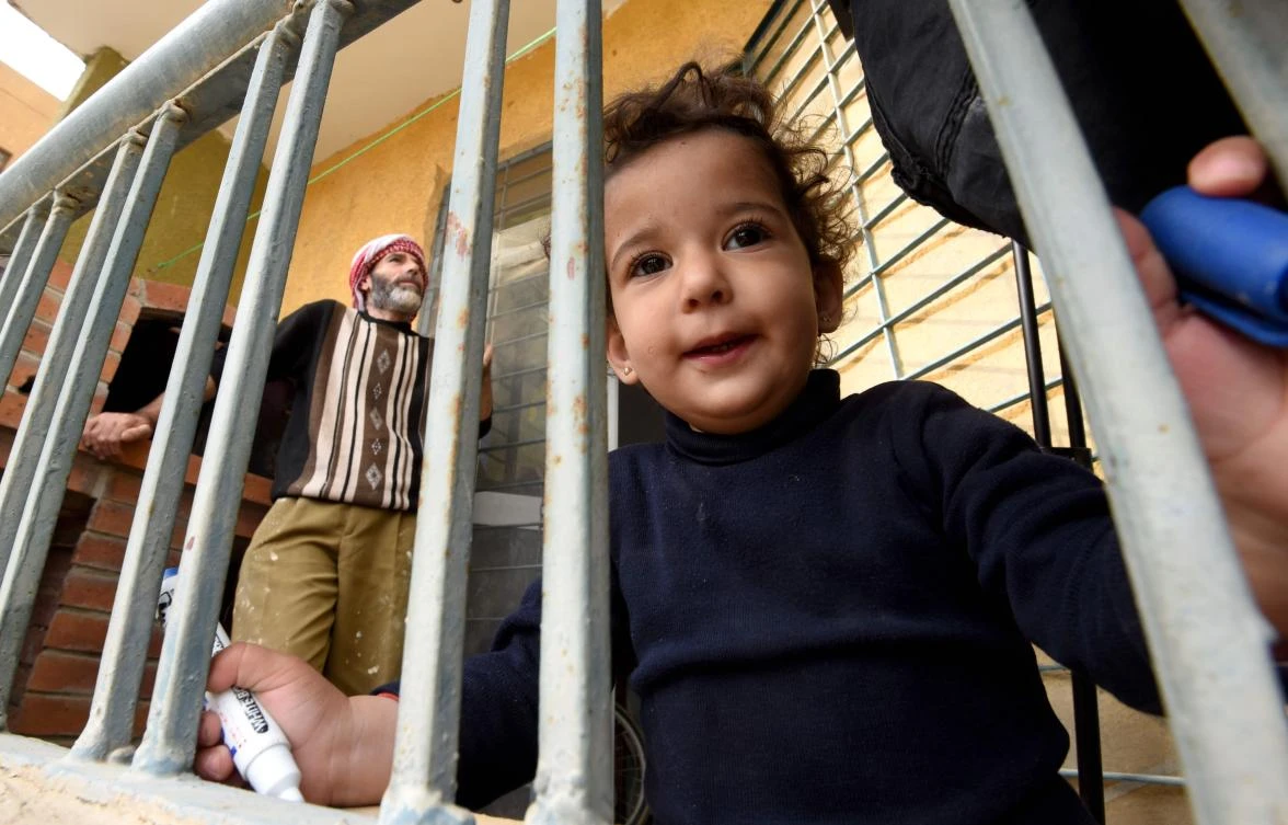 Syrian Mohamed Amin, 43, who fled his country with his family due to the war, stands next to a baking-oven at a make-shift bakery set up on the balcony of his apartment in the Egyptian capital Cairo, on March 8, 2017. (AFP)