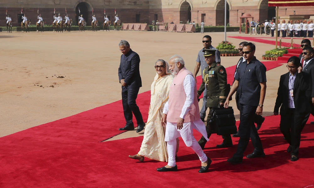 Indian Prime Minister Narendra Modi walks with his Bangladeshi counterpart Sheikh Hasina at the Presidential Palace in New Delhi on Saturday. (AP Photo)