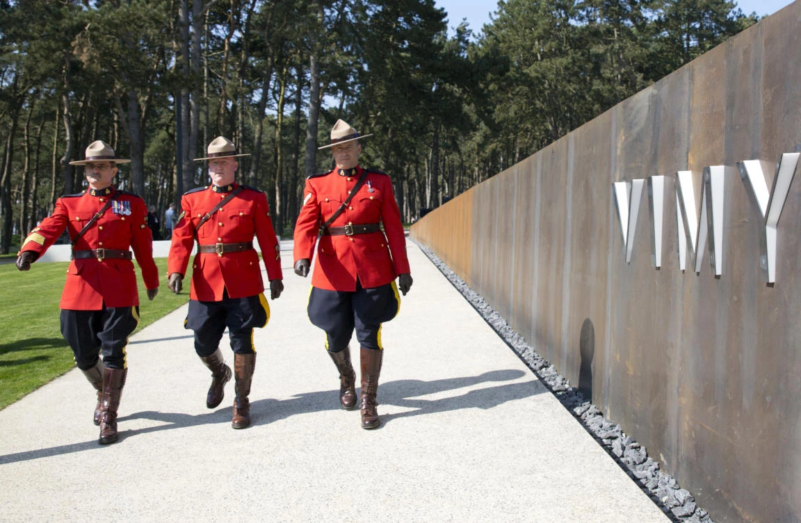 Canadian Mounted Police officers march by a sign which reads Vimy during the opening ceremony of the WWI Canadian National Vimy Memorial visitors center in Givenchy-en-Gohelle, France. (AP Photo/Virginia Mayo)