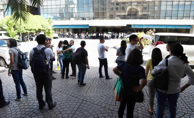Office workers stand on the grounds of an office building in the financial district of Makati in Manila. (AFP)