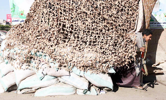 A Shi'ite Houthi rebel walks out of a canopy near sandbags near a checkpoint in Sanaa, in this December 11, 2014 file photo. (Reuters)