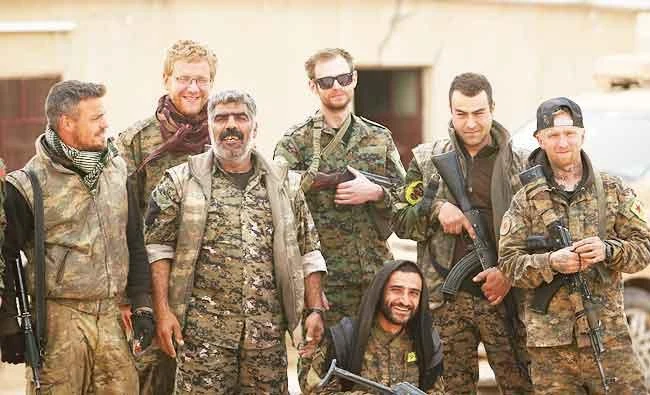 Syrian Democratic Forces (SDF) fighters pose with foreign volunteer fighters inside Tabqa military airport after taking control of it from Islamic State fighters, west of Raqqa city, Syria on Sunday. (Reuters)