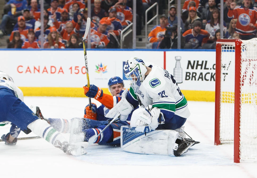 Connor McDavid (97) of the Edmonton Oilers crashes into Richard Bachman (32) of the Vancouver Canucks at Rogers Place in Edmonton, Alberta, Canada, on Sunday. (AFP)