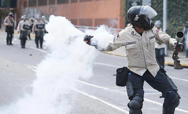A Bolivarian National Police throw a teargas bomb toward demonstrators during a protest in Caracas, Venezuela. (AP)