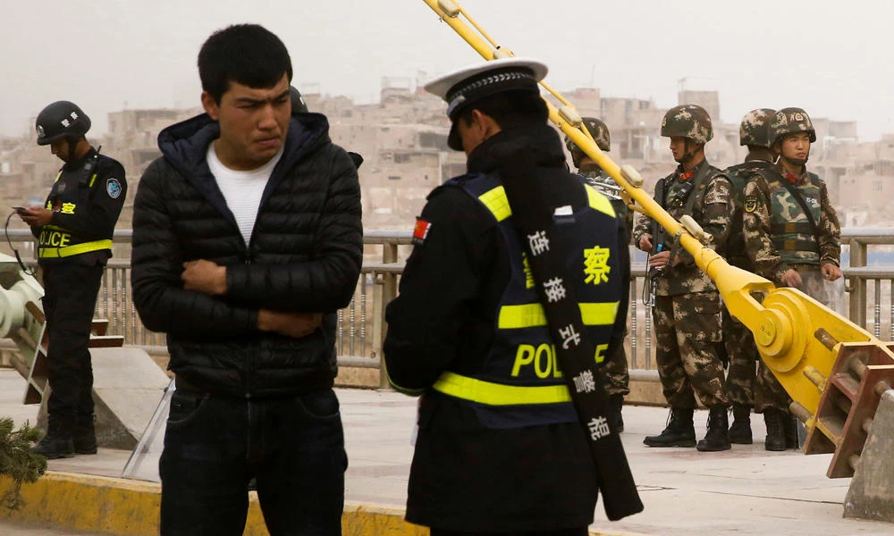 A police officer checks the identity card of a man as security forces keep watch in a street in Kashgar, Xinjiang Uighur Autonomous Region, China, on March 24, 2017. (REUTERS/Thomas Peter)
