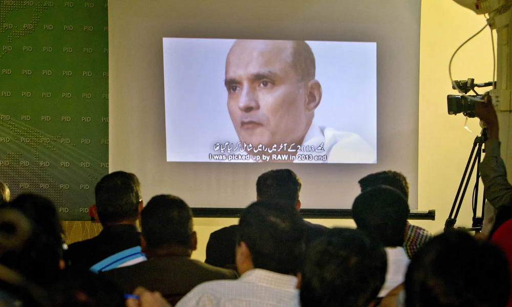 In this March 29, 2016 photo, journalists look a image of Indian naval officer Kulbhushan Jadhav, who was arrested in March 2016, during a press conference by Pakistan's army spokesman and the Information Minister, in Islamabad, Pakistan. The army said in a statement Monday that Jadhav was sentenced to death on charges of espionage and sabotage. Pakistan says Jadhav was an Indian intelligence official who aided and financed terrorist activities. (AP Photo/Anjum Naveed)