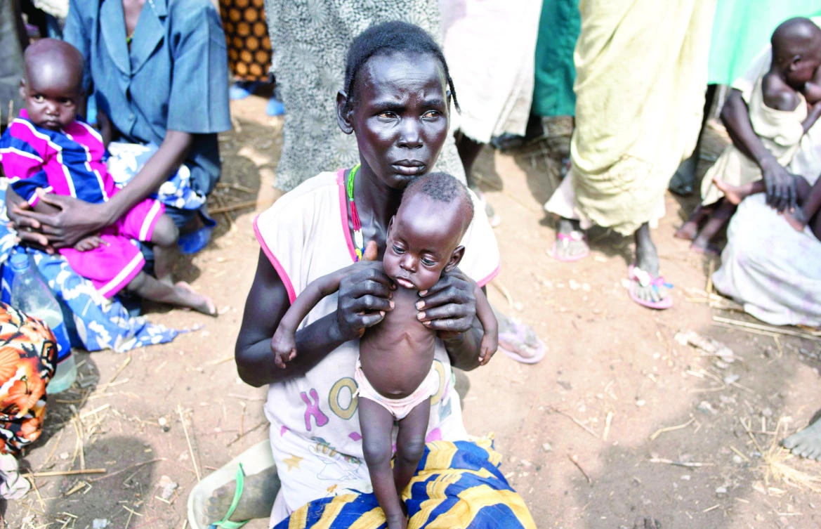 A woman holds her seven-month-old son as she and others walk to a food distribution site in Malualkuel in the Northern Bahr El-Ghazal region of South Sudan. (AP)