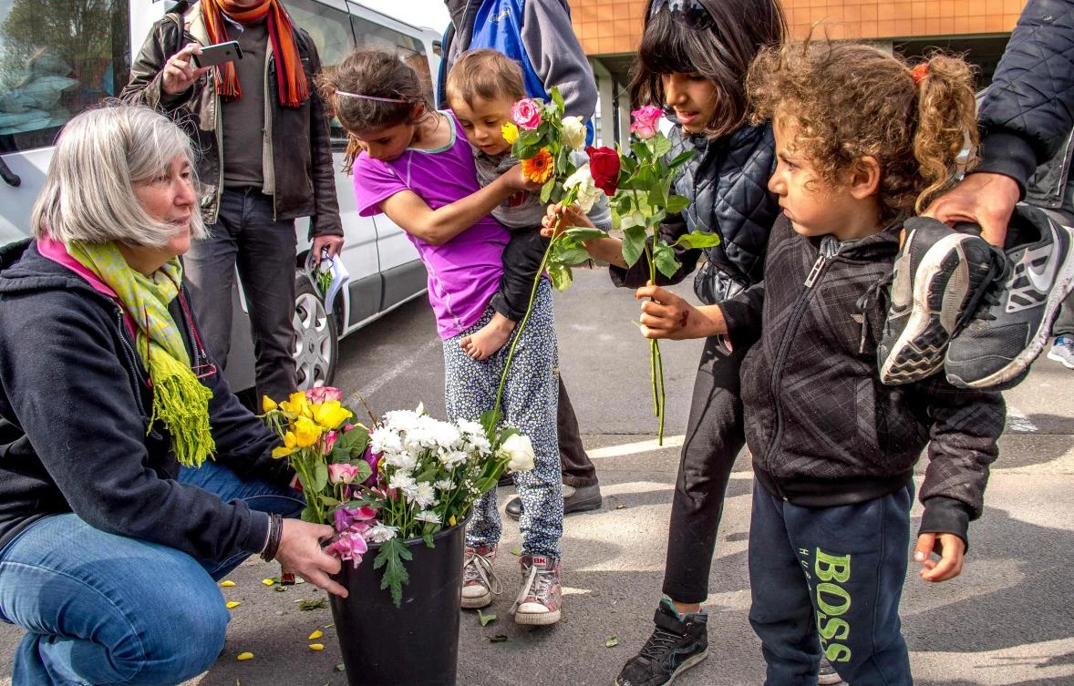 A woman from an association distributes flowers to migrant children. (AFP)