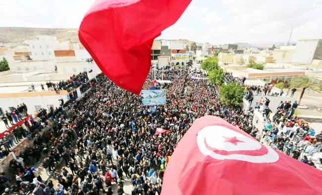 Tunisians wave their national flag as they take part in a general strike against marginalization and to demand development and employment on Tuesday, in Tataouine, south of Tunisia. (AFP)