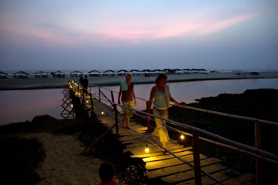 Western tourists walking along a wooden bridge at dusk at Mandrem Beach in the Indian state of Goa. (AFP)