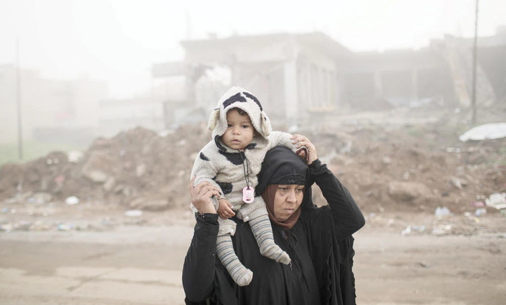 A woman carries her daughter as they flee fighting between Iraqi security forces and Daesh militants,
on the western side of Mosul, Iraq, on April 2. (AP)