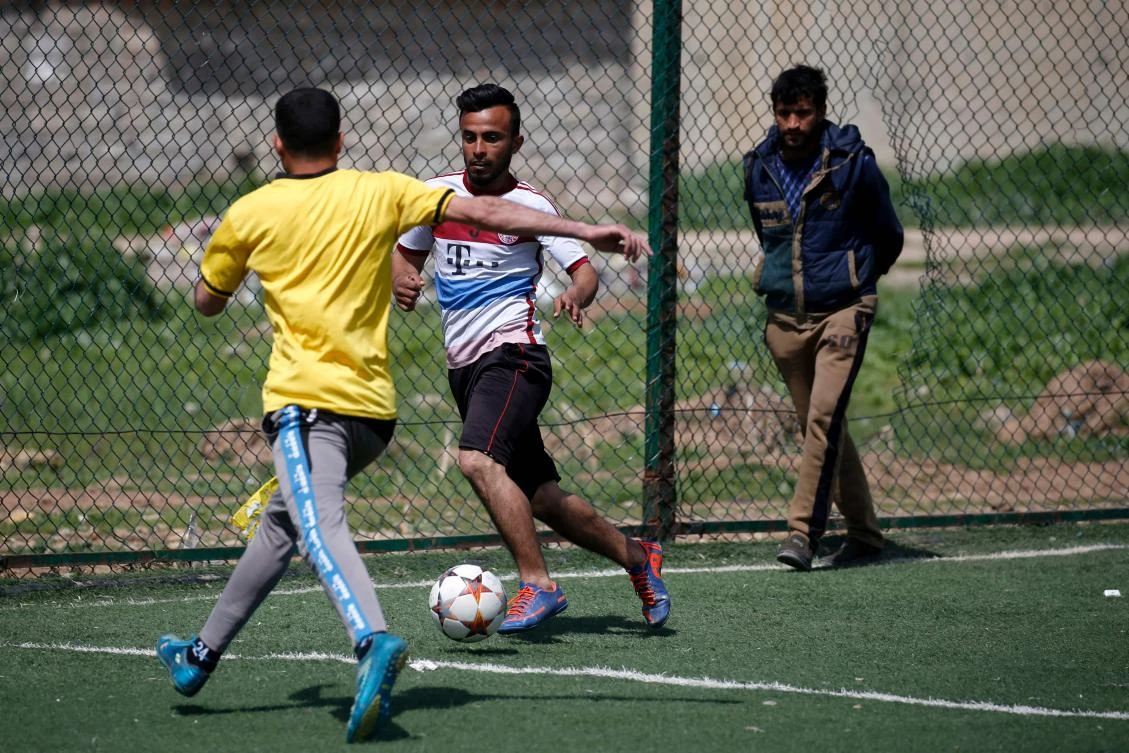 An Iraqi player (C), sporting the jersey of German club Bayern Munich, dribbles past a defender during a football match in eastern Mosul’s Al-Salam neighborhood on April 7, 2017. (AFP)