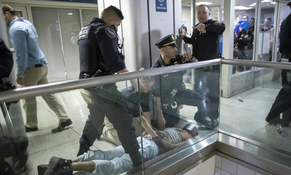 New York City police officers detain a passenger from a disabled New Jersey Transit train who became belligerent and sparked a stampede among passengers leaving the overcrowded station once the train finally arrived at New York's Penn Station on Friday. (AP Photo/Mary Altaffer)