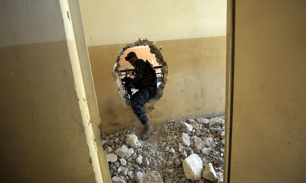A member of the Iraqi forces makes his way through a hole in the wall in a house in the old city of Mosul on Saturday during an offensive to recapture the city fromDaesh militants. (AFP / AHMAD AL-RUBAYE)