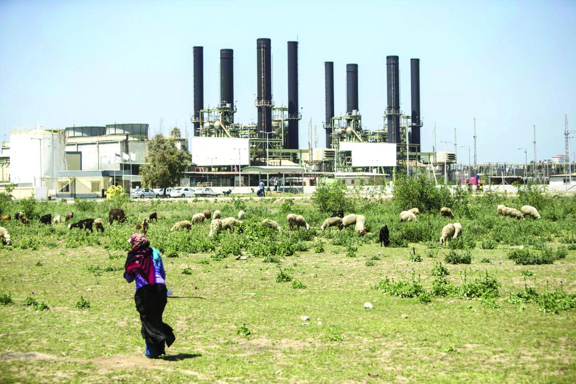 A Palestinian woman walks past a power plant in Gaza City, on Sunday. (AFP)