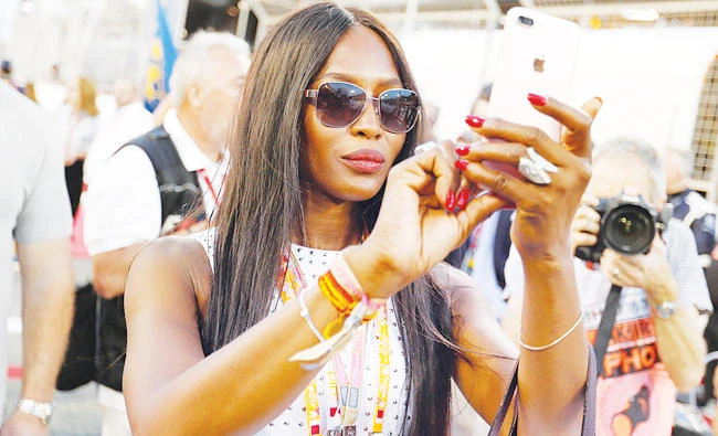 British supermodel and actress Naomi Campbell takes photo with her phone as she arrives at grid formation at the Bahrain F1 Grand Prix. (Reuters)