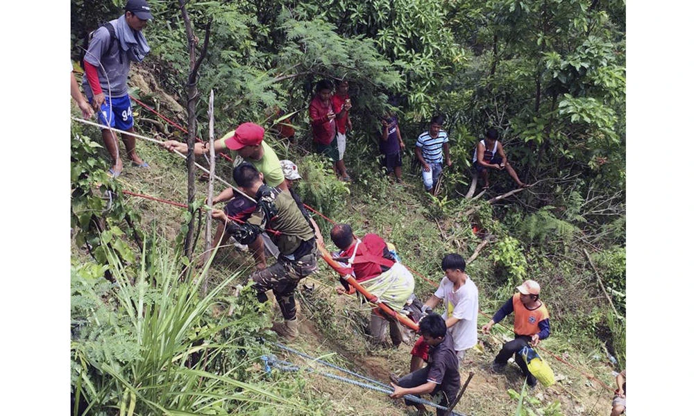 Rescuers use a rope as they pull survivors from a ravine where a passenger bus fell killing dozens in Carranglan, Nueva Ecija province, northern Philippines on Tuesday. (Philippine Red Cross Nueva Vizcaya chapter via AP)