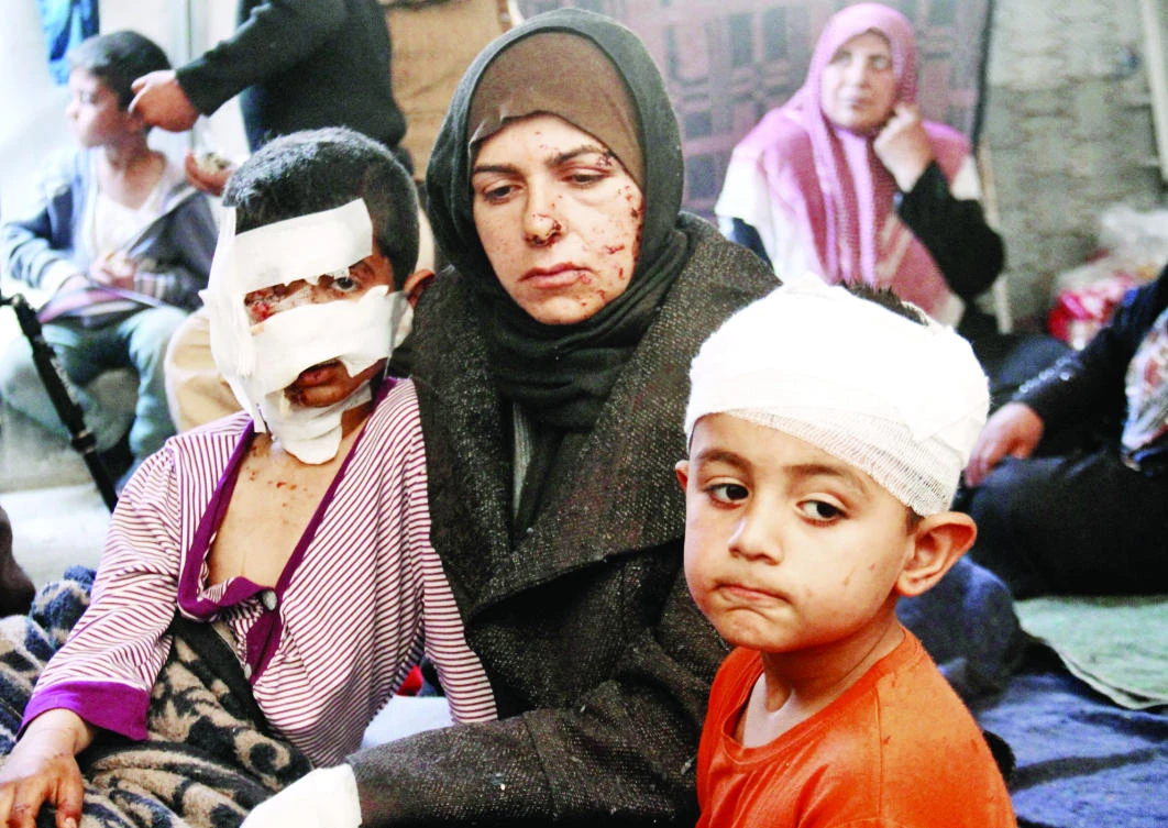 Syrians, who were injured in a suicide car bombing that targeted buses carrying evacuees, sit in a tent on the Syrian-Turkish border in Idlib Monday. (AFP)