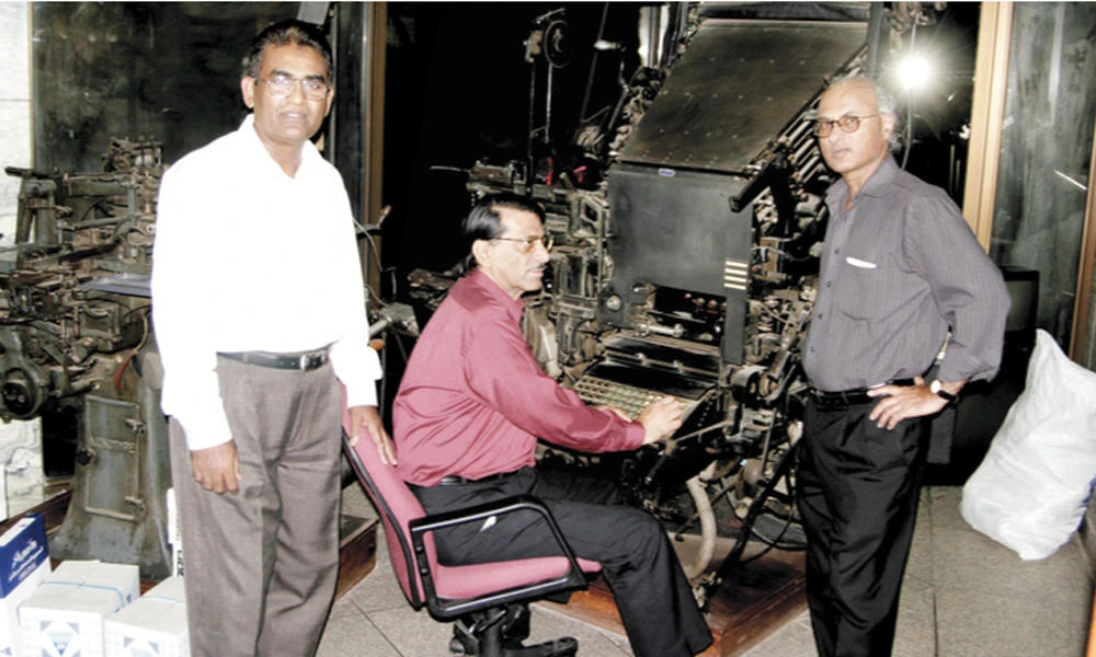 Abdul Jabbar Hussain Dawood, left, and his former colleagues, Abdul Mateen Munshi, center, and Syed Ather Ali, with a Linotype machine. This photo was taken in April 2005.