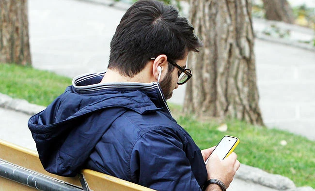 An Iranian man uses a smart phone at a park in Tehran, in this file photo. (AFP)