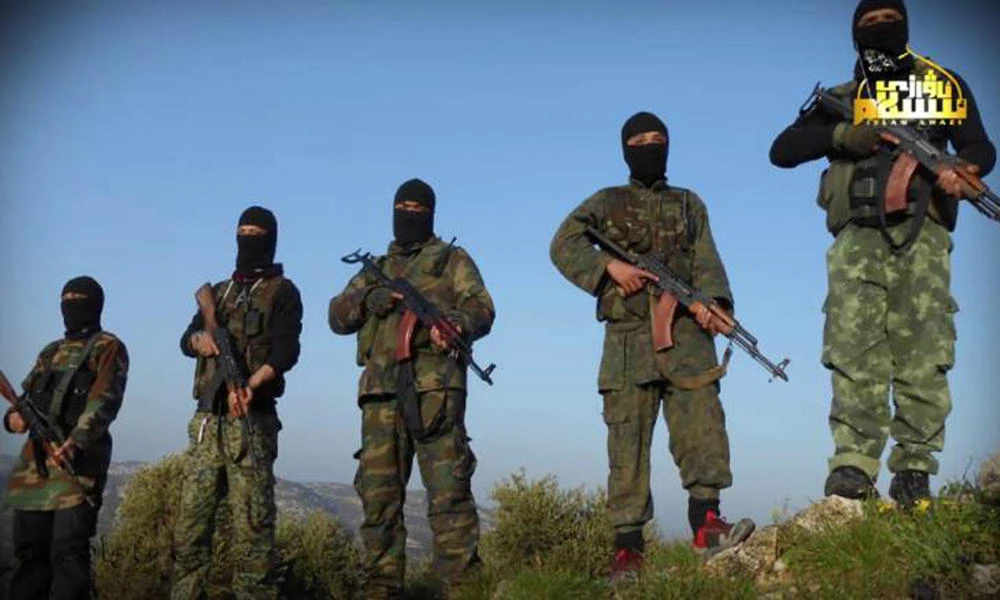 In this undated photo released by Turkistan Islamic Party, a militant website shows fighters from the Turkistan Islamic Party holds their weapons, at unknown place in Syria. (Militant Website Turkistan Islamic Party via AP)